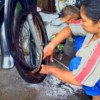 Istri tukang tambal ban ikut membantu suaminya menambal ban.